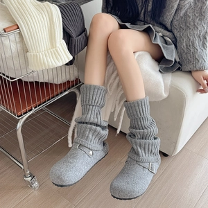 Detail of gray cable knit leg warmers with buckle felt clogs for a cozy winter outfit