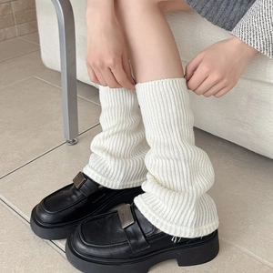 Detail of white ribbed knit leg warmers showing soft vertical texture and loose fit
