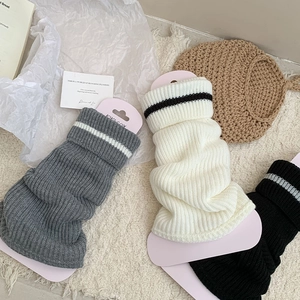 Detail of striped knitted leg warmers in grey, white and black with KIKI SOX packaging