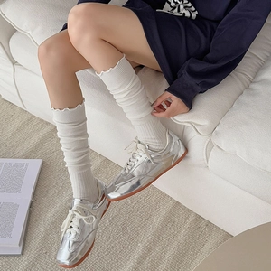 Detail of silver metallic sneakers paired with white ruffle trim leg warmer socks