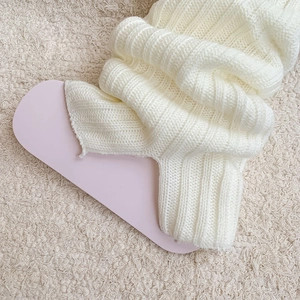 Detailed macro view of cream-colored thick ribbed knit leg warmers with split hems