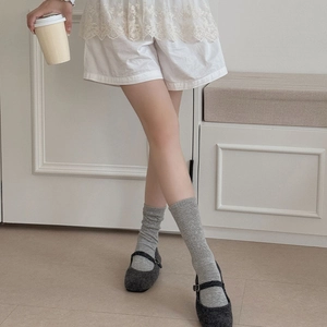 Detail of grey hollow-out knit mid-tube socks paired with dark grey Mary Jane shoes