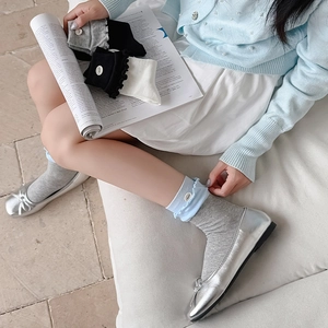 Detailed view of ruffle edge cotton socks with button accents in blue and grey