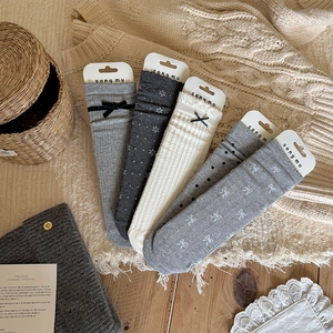 Close-up of five pairs of grey and beige ribbed knit socks with bows and floral patterns