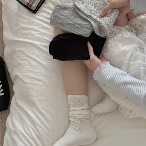 Detailed knit pattern of white, gray, and black hollow crew socks for women
