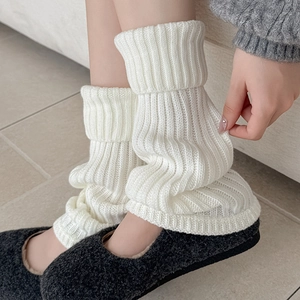 Detail of white chunky knit leg warmers with ribbed texture and flared cuffs on model