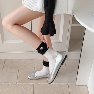 Close-up of metallic silver ballet flats with bow and decorative ruffle sock layering