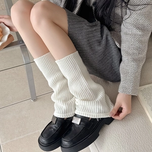 Detail of white ribbed knit leg warmers paired with black loafers for winter style