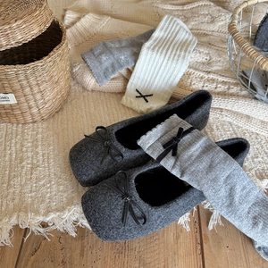 Detailed texture of grey knit socks with bow tie accents next to vintage flat shoes