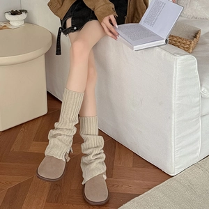 Detail view of beige ribbed knit leg warmers with split design and thick warm texture