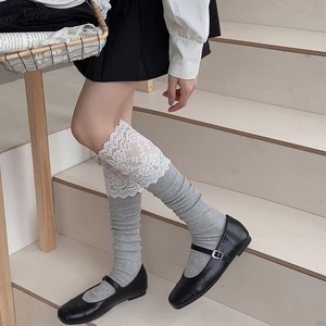 Detail of grey ribbed knee-high socks with delicate white lace trim and dark Mary Jane shoes