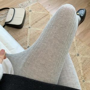 Detail showing the vertical ribbed texture and high elasticity of grey knitted tights