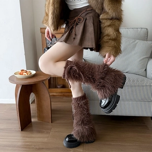 Brown faux fur leg warmers with bows for winter, styled with a pleated skirt and boots