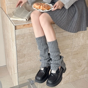 Detail of grey ribbed knit leg warmers with slit paired with platform loafers and skirt