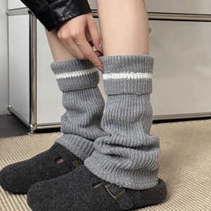 Detail of grey knitted leg warmers with white stripes paired with grey felt clogs
