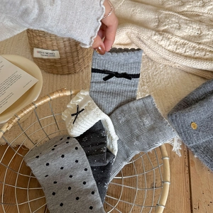 Detailed close-up of grey and white knit socks with lace edges and delicate bows