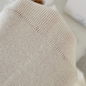 Macro shot of off-white ribbed knit fabric detail and stitching for women's crew socks