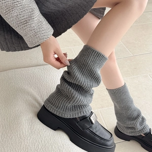 Detail of grey knitted leg warmers featuring vertical ribbed texture and slouchy winter style