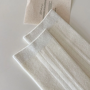 Detail of cream rib-knit knee-high socks showing soft texture and high-stretch fabric