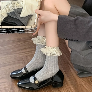 Detailansicht grauer Streifensocken mit Spitzenborte und Seidenschleife am Bündchen