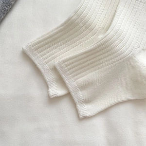 Close-up of white ruffled leg warmers with ribbed knit texture and ballet core design