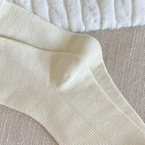 Detail of cream white ribbed knit mid-calf socks with textured weaving and soft fabric