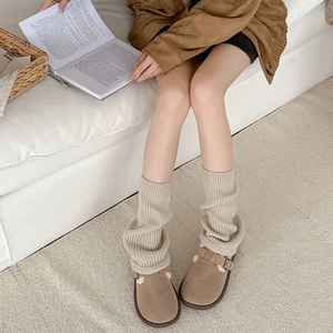 Cozy winter knit leg warmers in beige paired with fleece-lined brown suede clogs for women