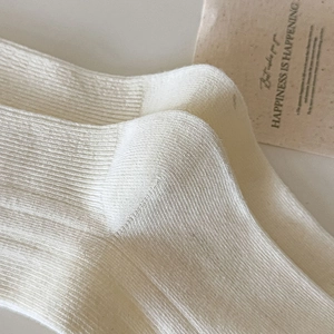 Close-up of cream ribbed knit knee-high socks showing textured fabric and heel detail
