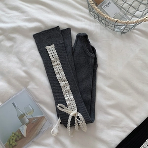 Details von dunkelgrauen Strick-Stulpen mit weißer Spitze und Schleifenverzierung