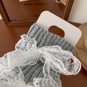 Vue macro de jambières en tricot gris avec des nœuds en dentelle blanche détaillée