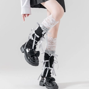 Detail of Lolita leg warmers with black knit fabric, white lace, and silk bows
