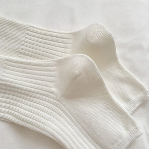 Macro detail of white ribbed knit fabric texture on ballet style leg warmers