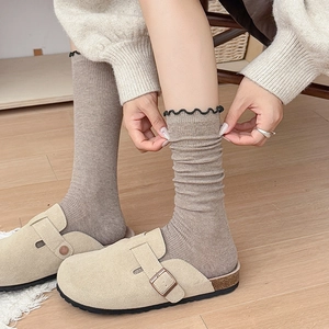 Détail du bord ondulé et de la texture côtelée sur chaussettes brunes et mules