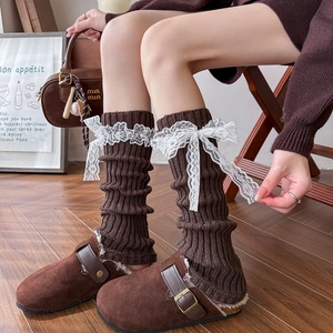 Brown knit leg warmers with lace bows paired with fleece-lined mules on wooden floor