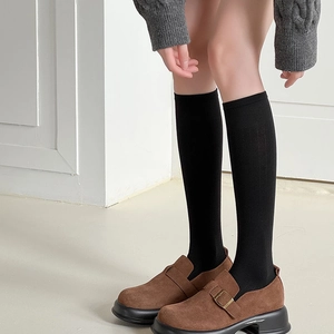 Gros plan sur des chaussettes hautes noires côtelées avec mocassins marron à plateforme