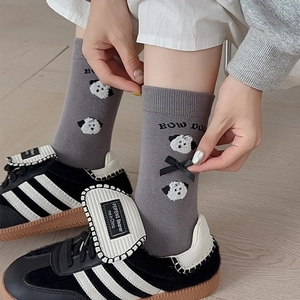 Detail of grey knitted socks featuring puppy embroidery and a delicate black satin bow