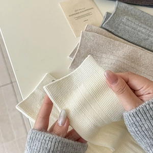 Detail showing the high elasticity of ribbed knit knee high socks in beige and cream