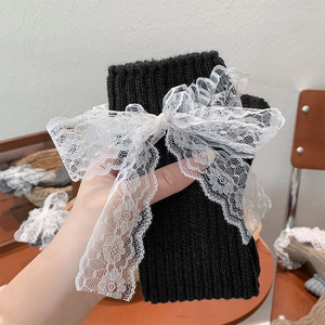 Détail de jambières en tricot noir avec nœuds en dentelle blanche et maille côtelée