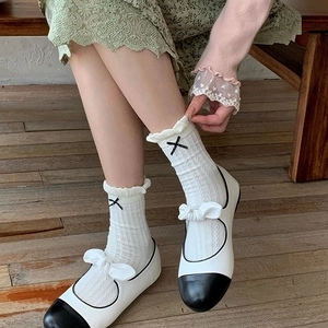 French vintage white Mary Jane shoes with black ribbon socks on wooden floor