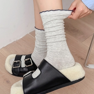 Détail de chaussettes en maille gris clair avec bordure ondulée bleu marine élégante