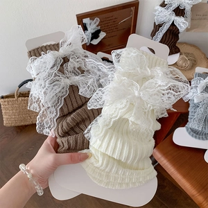 Détail de jambières en tricot avec des nœuds en dentelle en tons crème et café