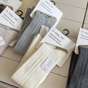 Close-up of ribbed knit knee-high socks in various neutral tones with retail packaging