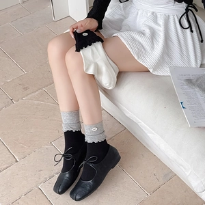 Detail of color-block knit socks featuring ruffled edges and decorative button accents