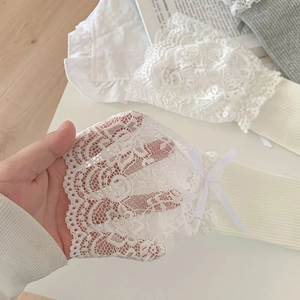 Detail of ballet style white lace socks with ribbon bow and rib-knit texture