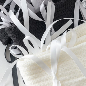Close-up of knit leg warmers with lace-up silk ribbons and bows in black and beige
