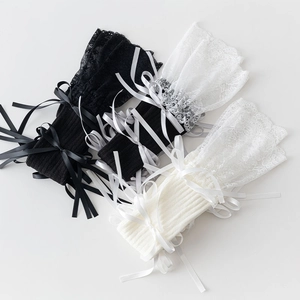 Detail of lace leg warmers with ribbon bow ties and floral lace trim in black and beige