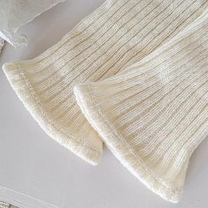 Primer plano de calentadores de punto acanalado blanco crema con textura de lana suave
