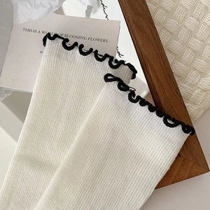 Détails de chaussettes en tricot blanc à côtes avec bordure noire ondulée élégante