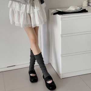 Detail of dark grey ribbed leg warmers with ruffle trim and Mary Jane shoes
