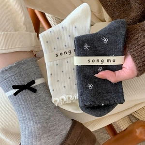 Dettaglio di calze con bordo a volant, fiocchi di velluto e motivi a pois in stile cozy